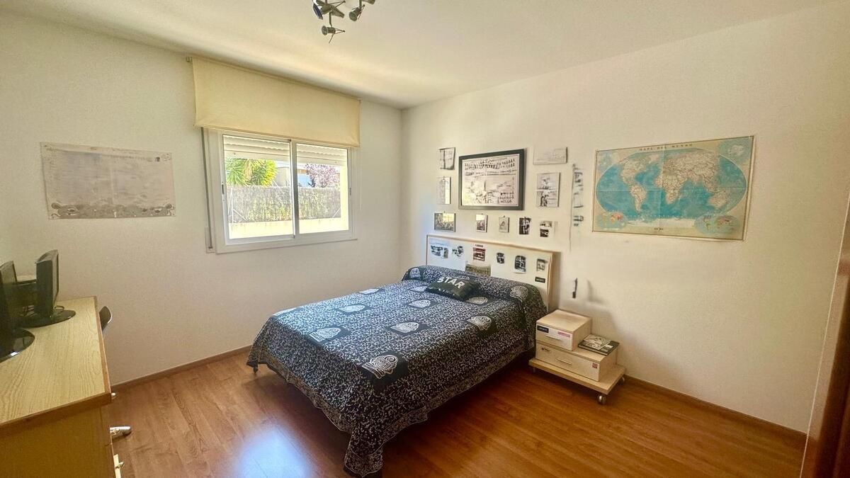 Un dormitorio con una cama, mesita de noche y ventana.