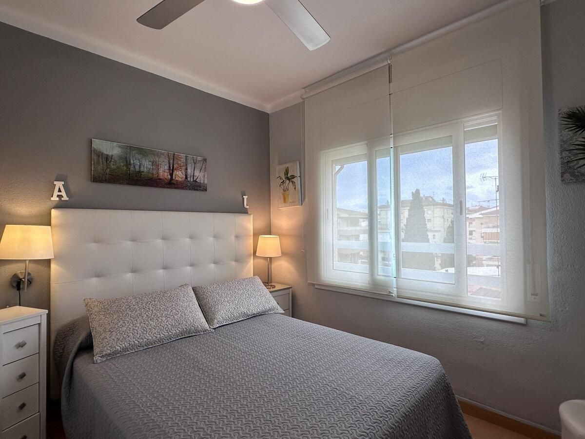 Dormitorio con combinación de colores gris y blanco, una cama y una ventana con vista.