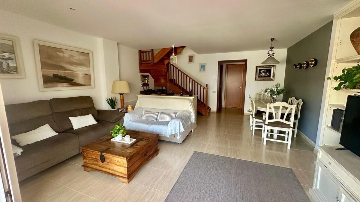 Una sala de estar con sofá, mesa, sillas y escaleras.