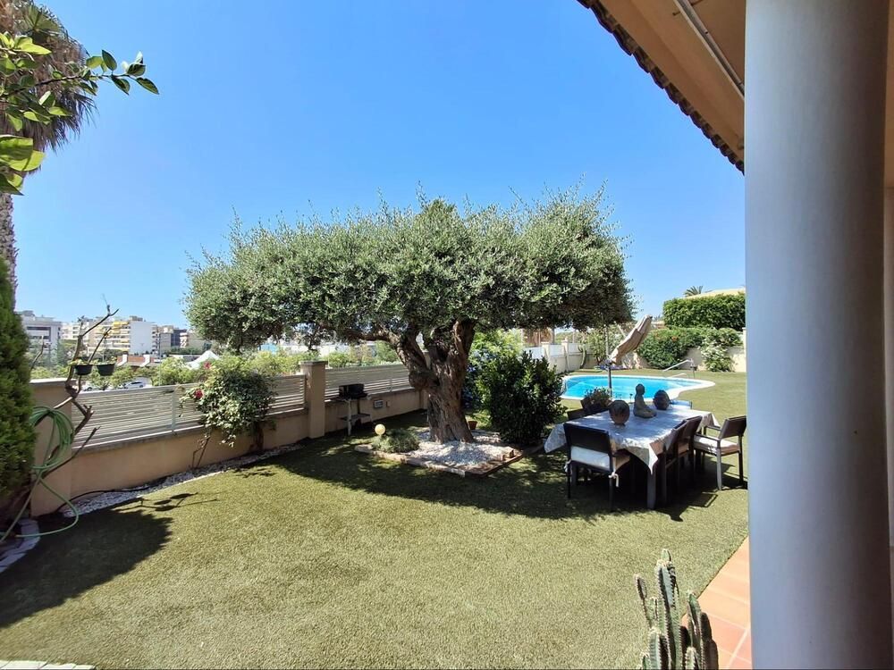 Hay una mesa y sillas en el patio trasero con una piscina al fondo.