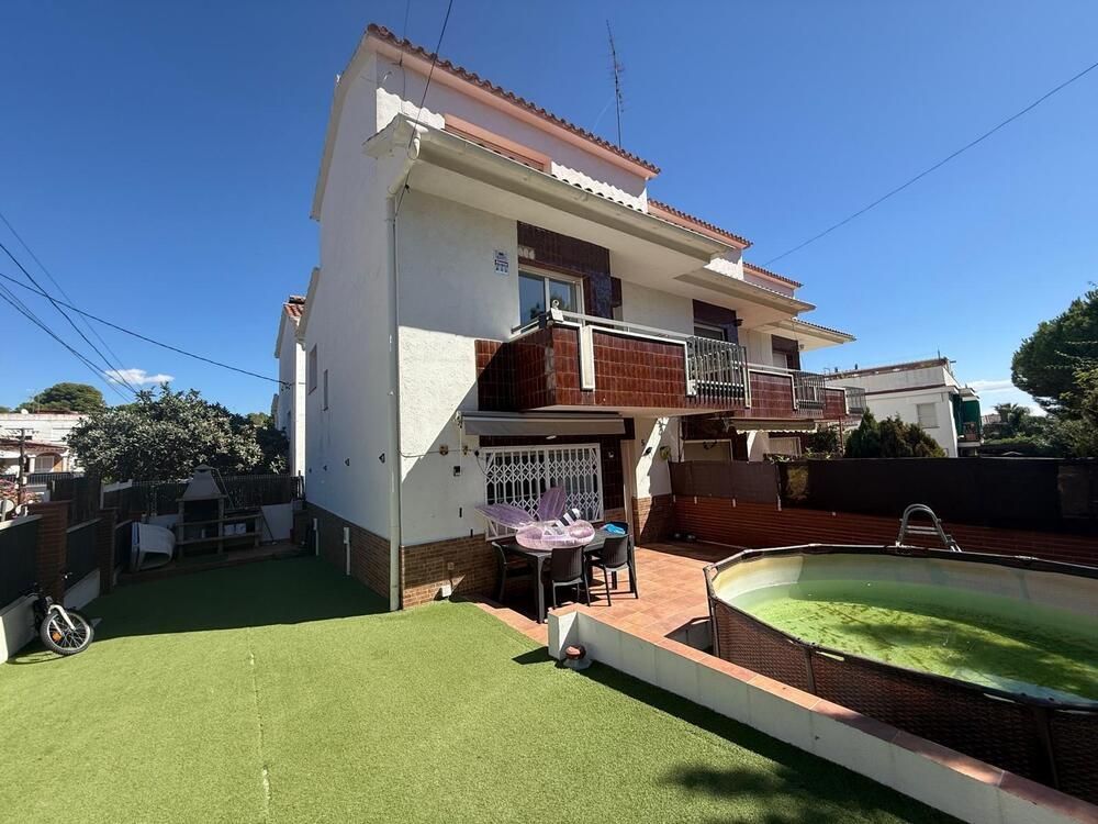 Casa blanca de dos pisos con piscina, patio trasero y un cielo azul claro.
