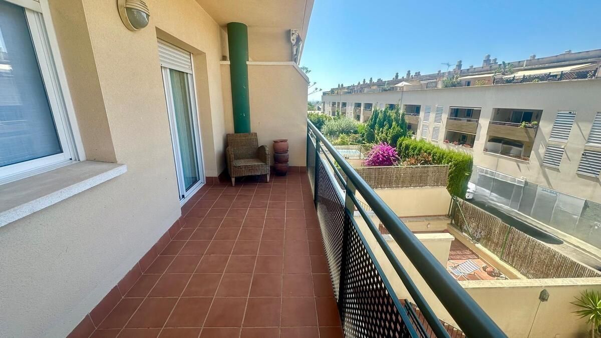 Un balcón con una barandilla verde y una silla encima.