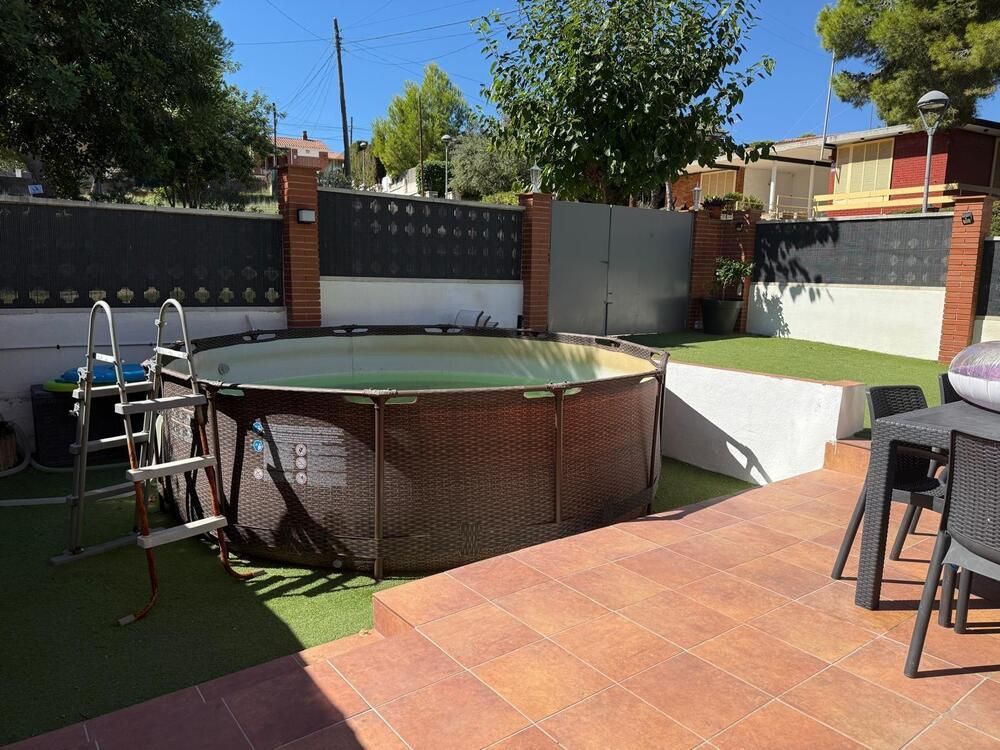 Piscina sobre el suelo en un patio trasero con césped artificial y patio.
