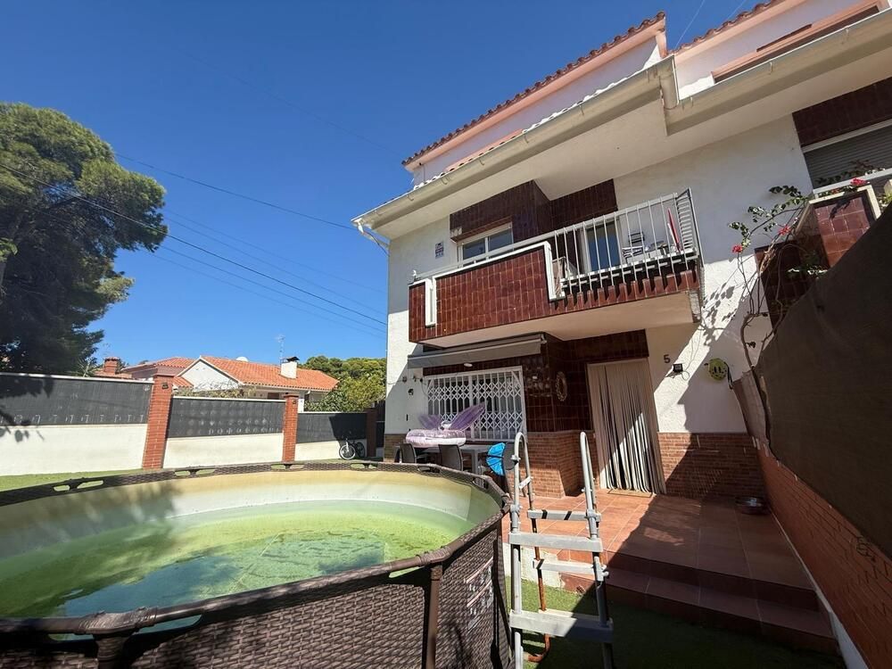 Casa blanca de dos pisos con piscina en un patio en un día soleado.