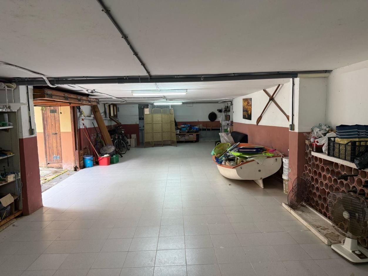 Amplio sótano con barco, herramientas y almacenamiento; ladrillos y tuberías a la vista; piso blanco, paredes neutrales.