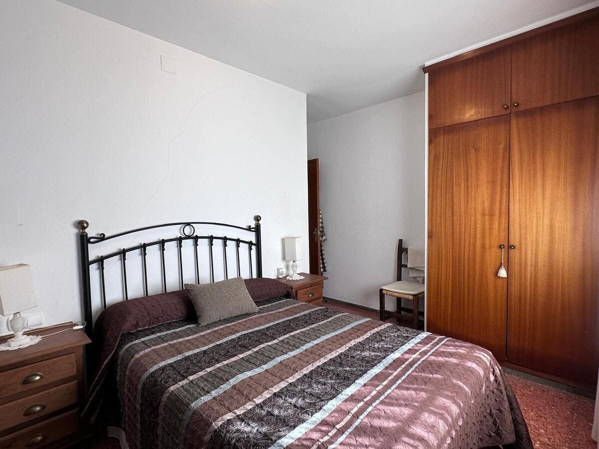 Dormitorio con cama, mesitas de noche, armario de madera y silla.