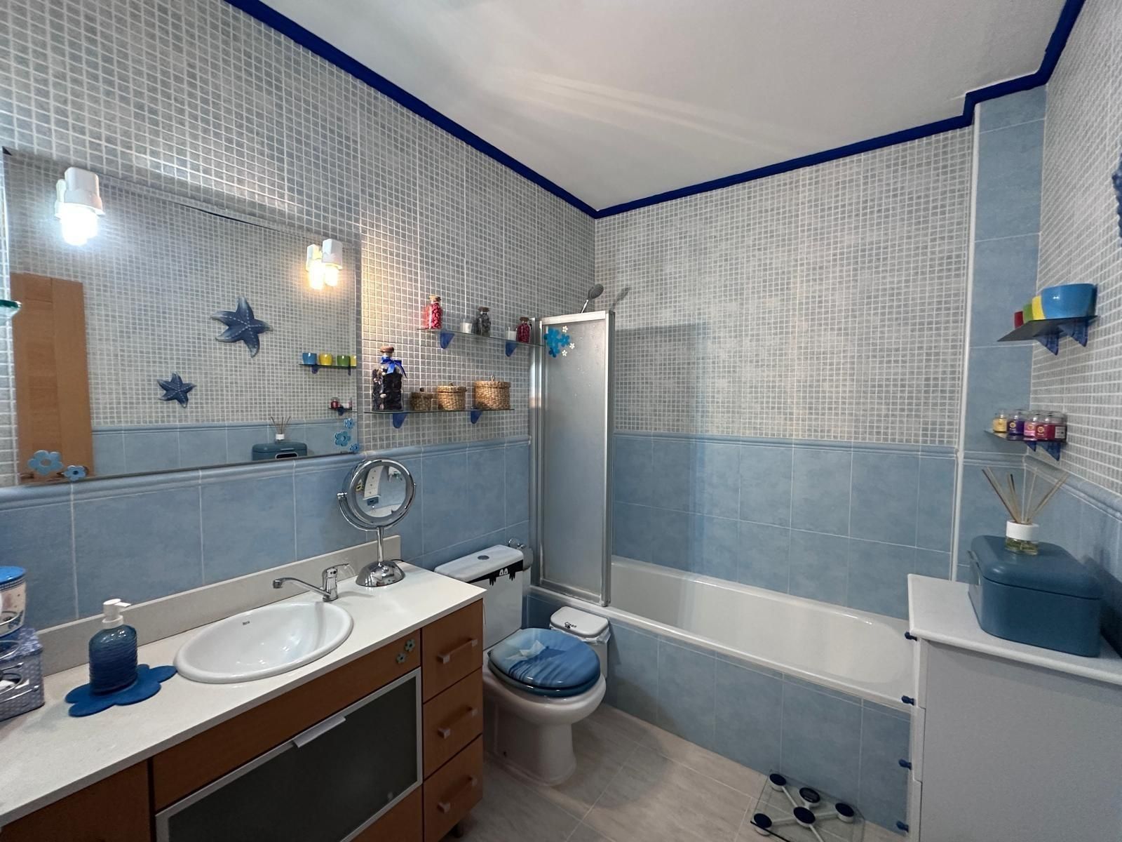 Un baño con azulejos azules con tocador, inodoro y bañera.
