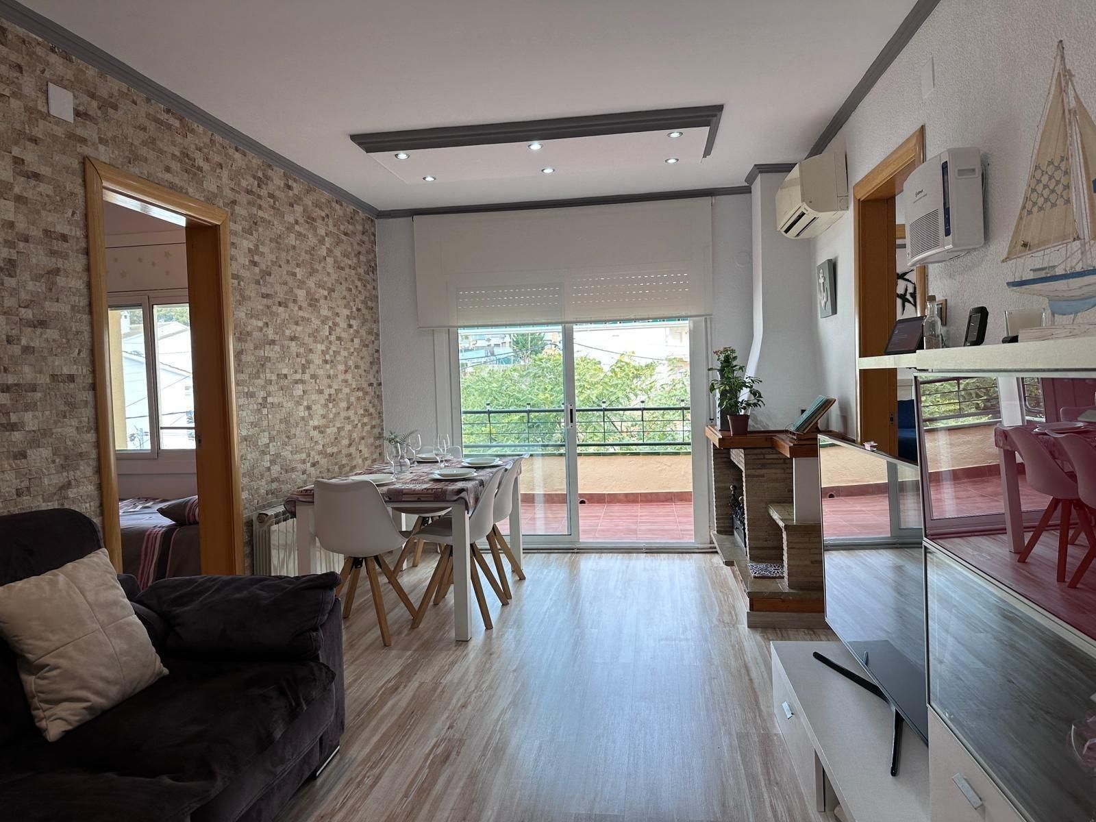 Sala de estar con mesa de comedor, sofá y puerta corrediza de vidrio a un balcón.