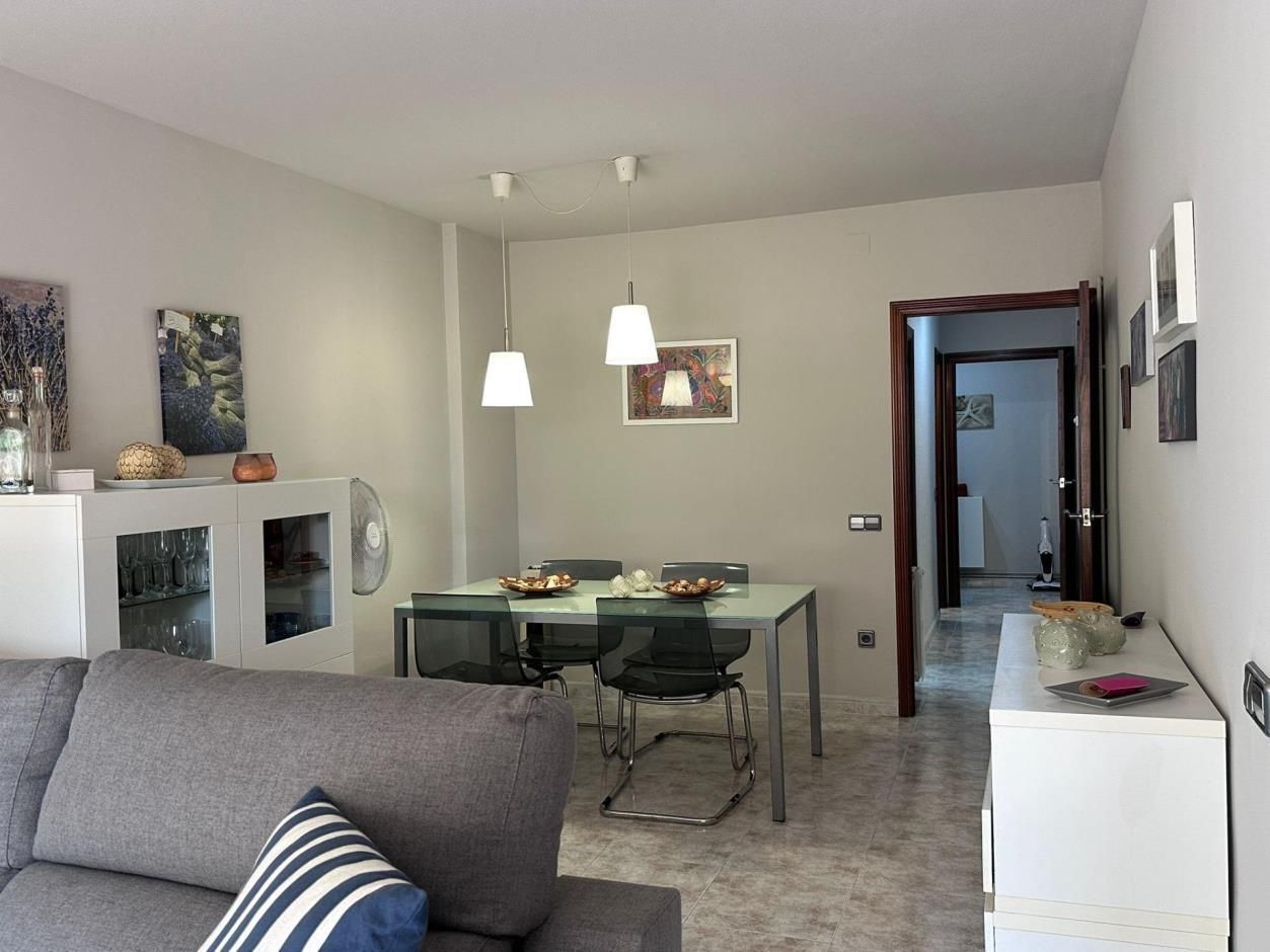 Sala de estar con mesa, sillas, sofá y obras de arte en las paredes.