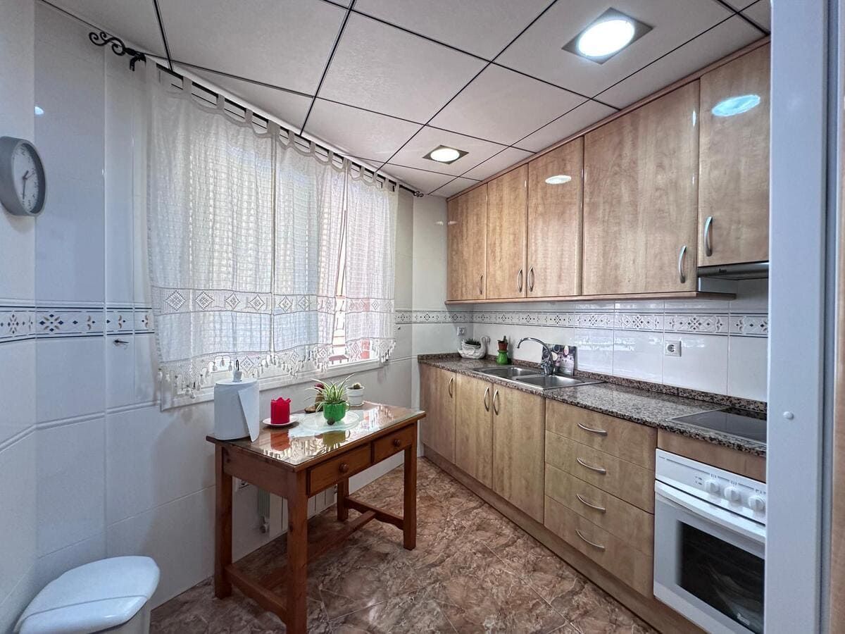 Pequeña cocina con muebles de madera y una mesa junto a la ventana.