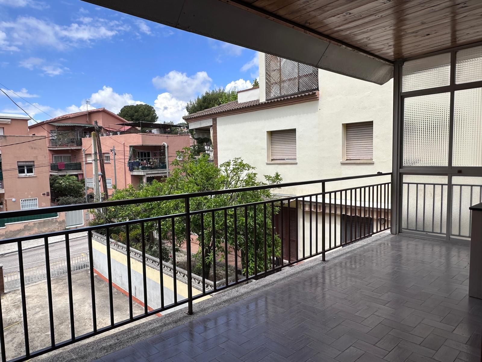 Balcón con barandilla negra con vista a edificios y cielo azul.