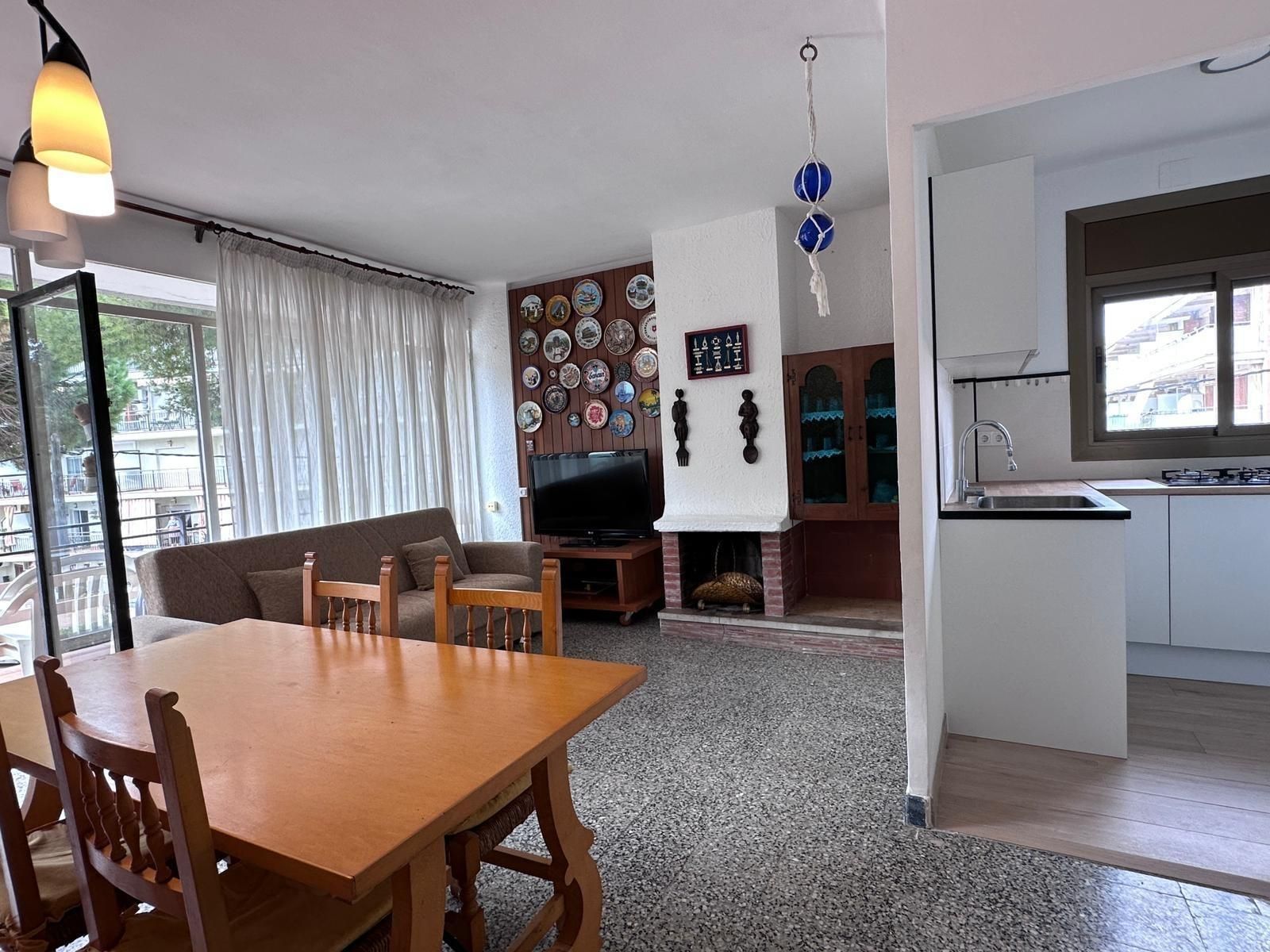 Sala de estar con mesa de comedor, sofá, chimenea y acceso a la cocina.