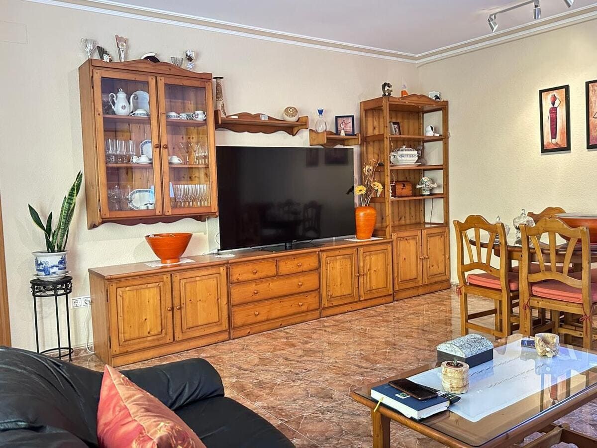 Sala de estar con muebles de madera, que incluyen mueble de TV, estantes y juego de comedor.