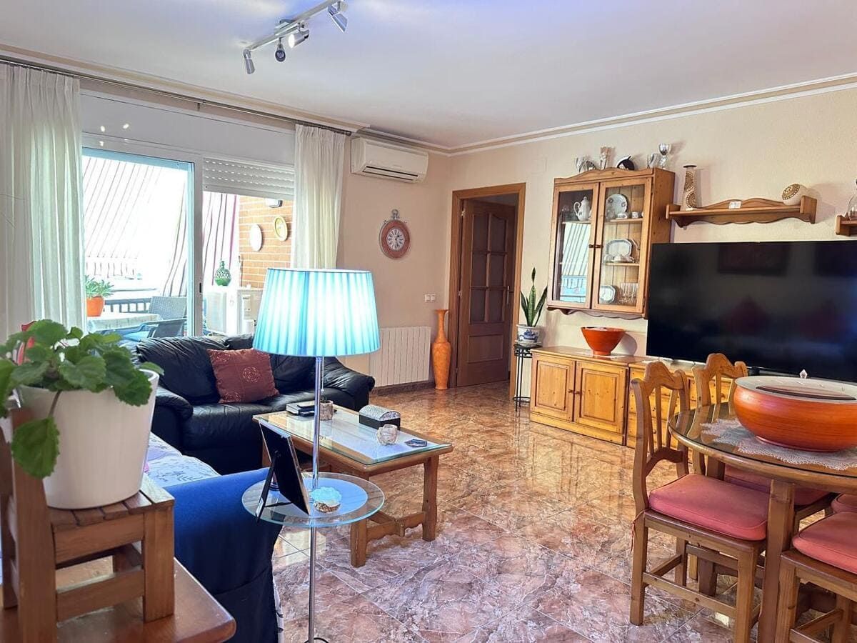 Sala de estar con sofá de cuero, TV, muebles de madera y balcón.