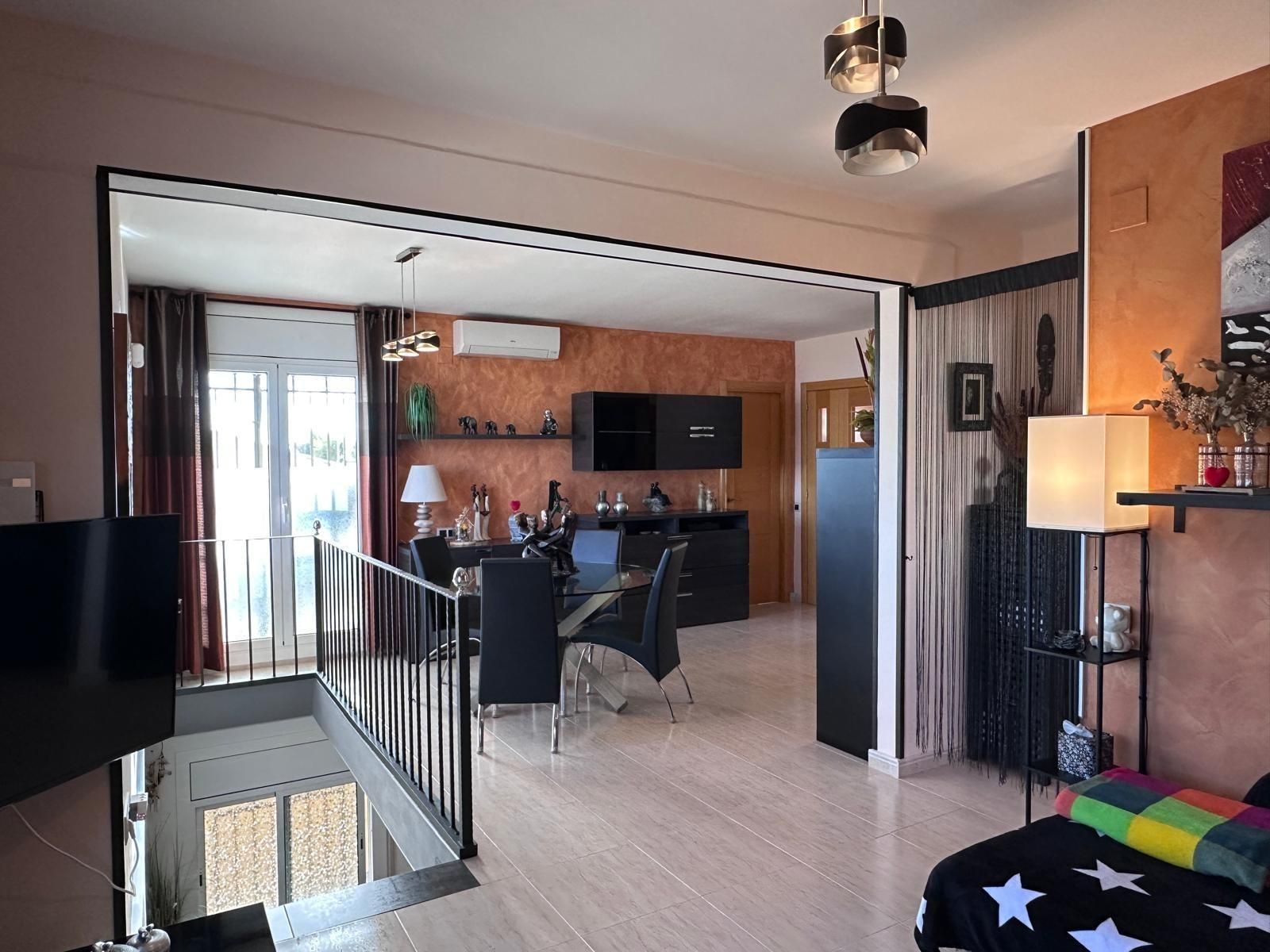 Espacio habitable de concepto abierto con comedor, acceso al balcón y muebles oscuros.