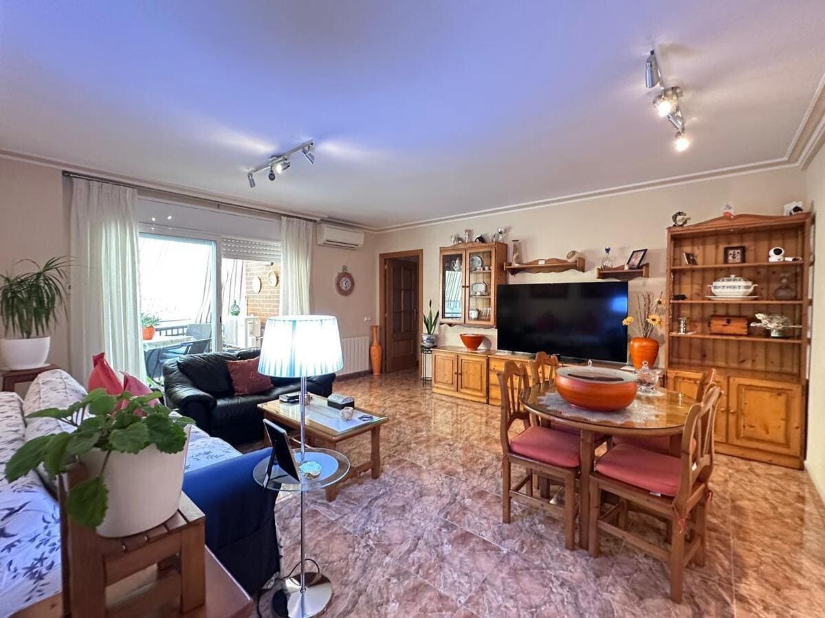 Sala de estar con muebles, TV y mesa de comedor. Soleada y con acceso al balcón.