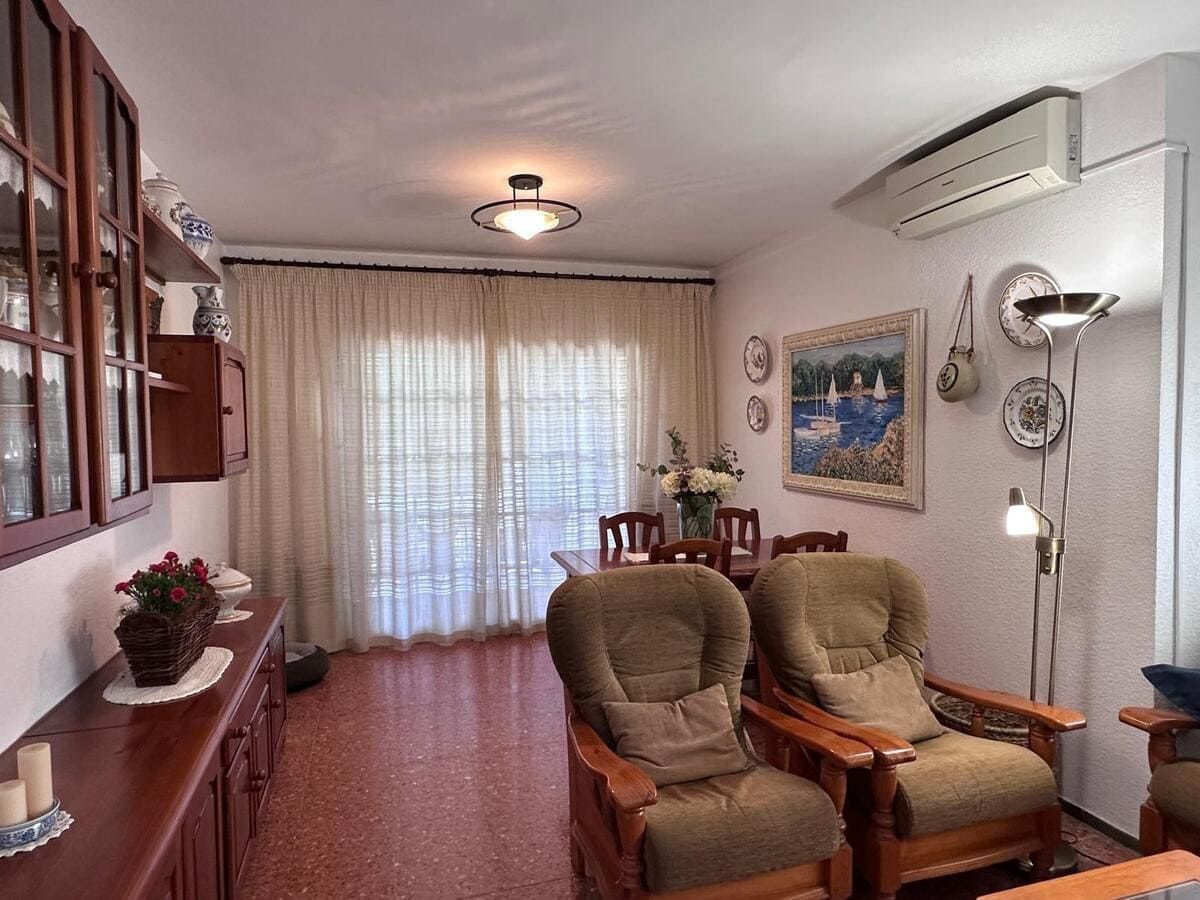 Sala de estar con muebles de madera, cortinas color crema y mesa de comedor.