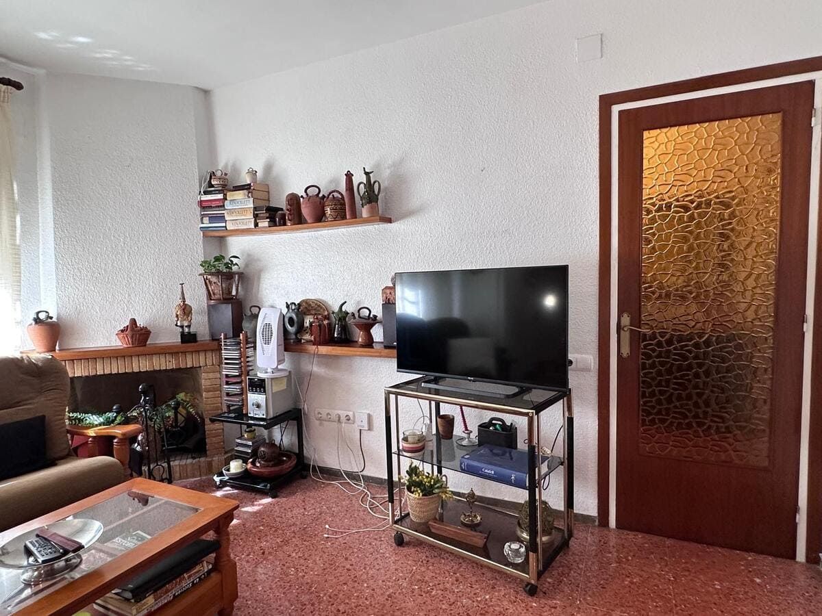 Sala de estar con TV sobre mueble, chimenea, estanterías con decoración y suelo estampado.