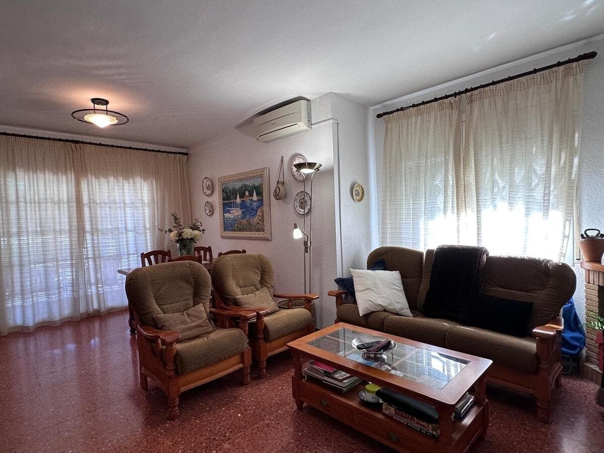 Sala de estar con muebles marrones, cortinas y mesa de café.