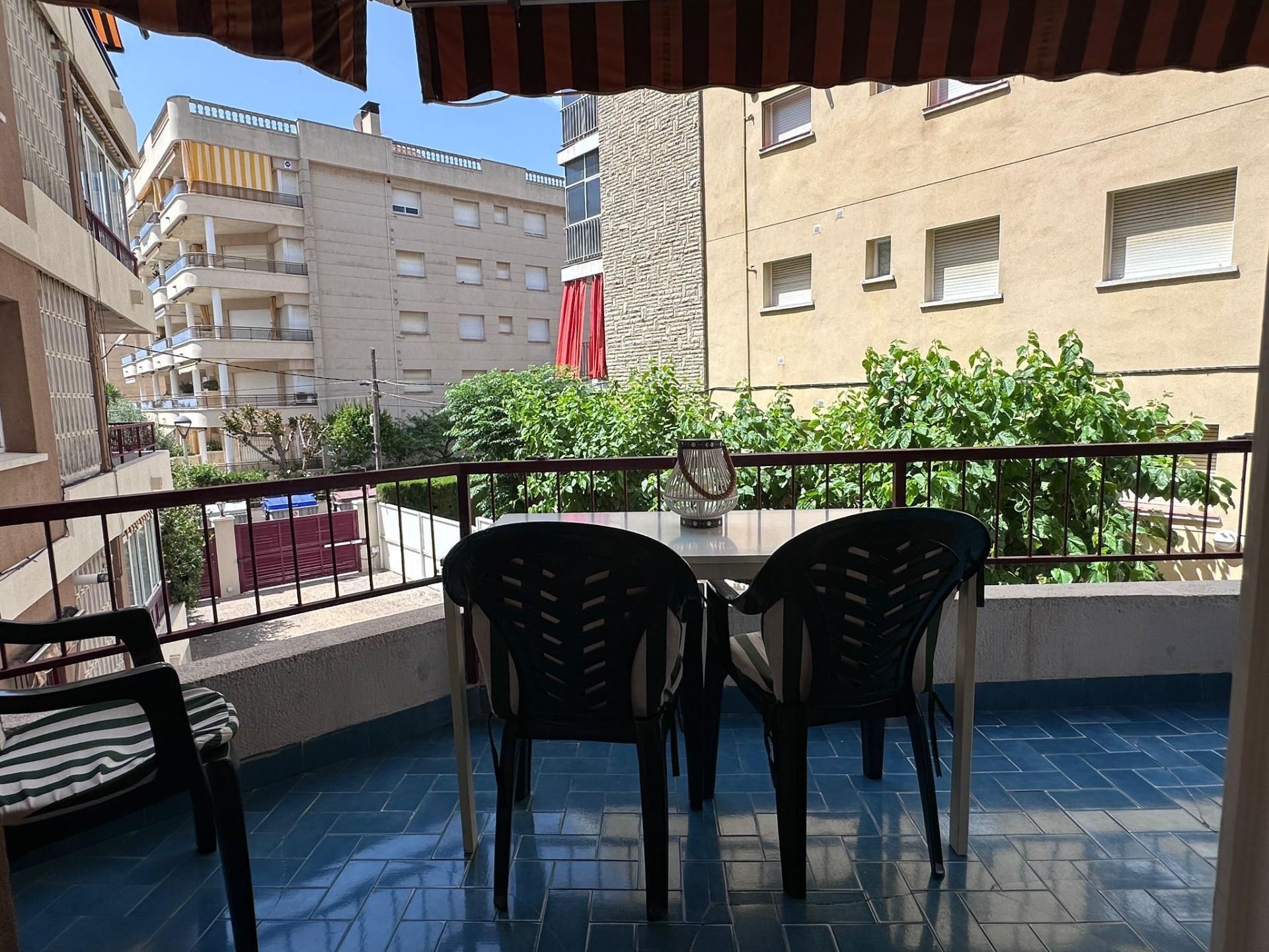 Un balcón con dos sillas y una mesa con vista a una ciudad.