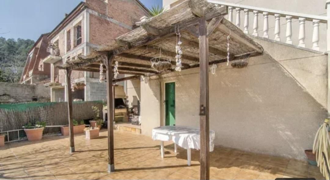 Patio con techo de paja, mesa y edificio con escalera.