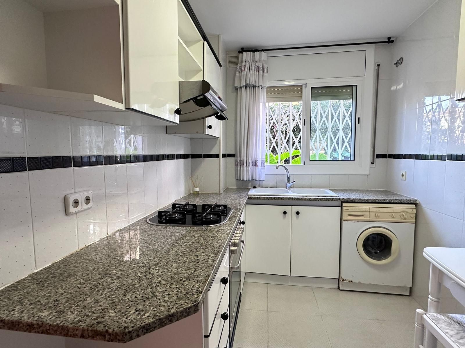 Una cocina con encimeras de granito y gabinetes blancos.