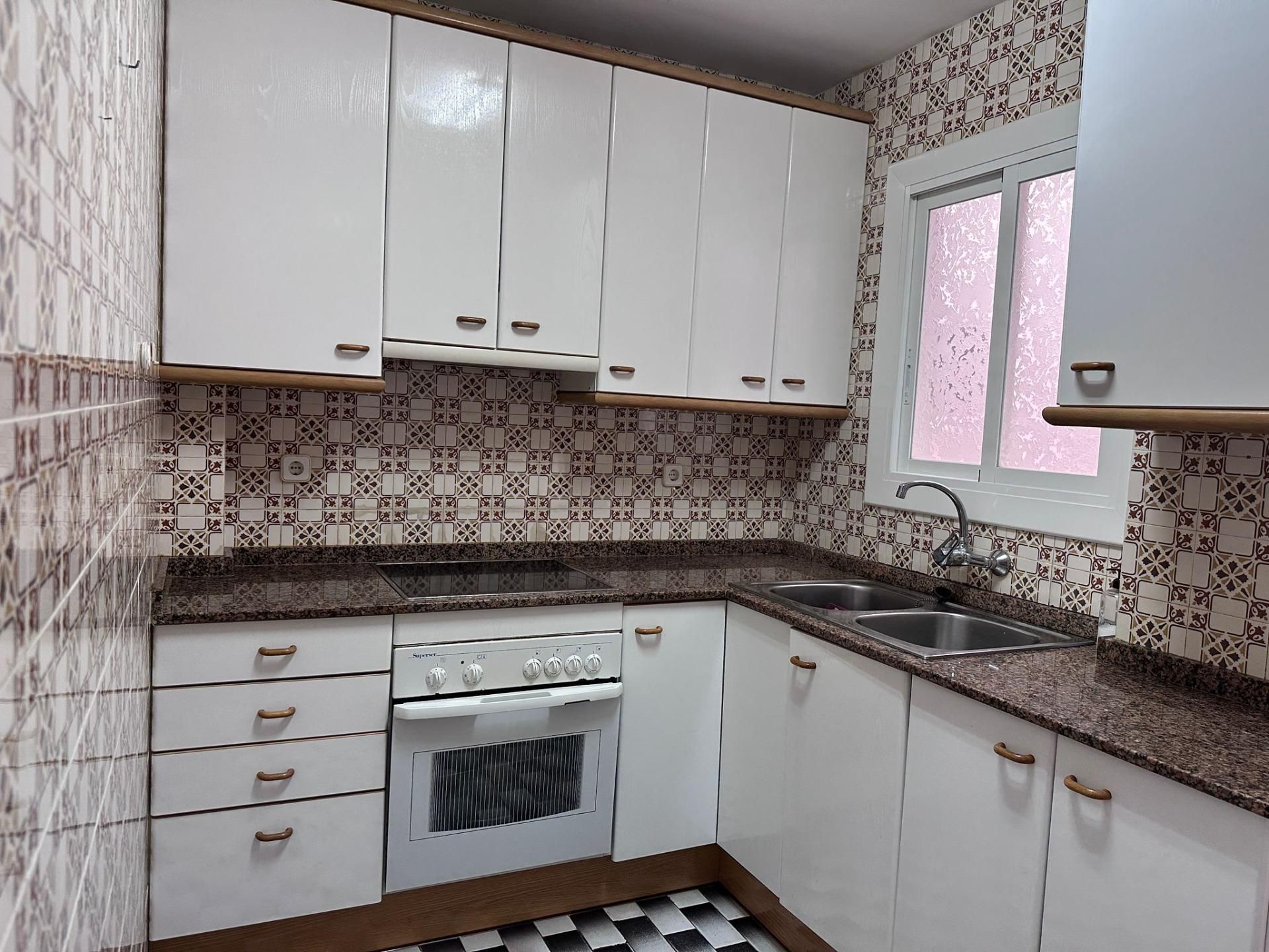 Una cocina con gabinetes blancos y encimeras de granito.