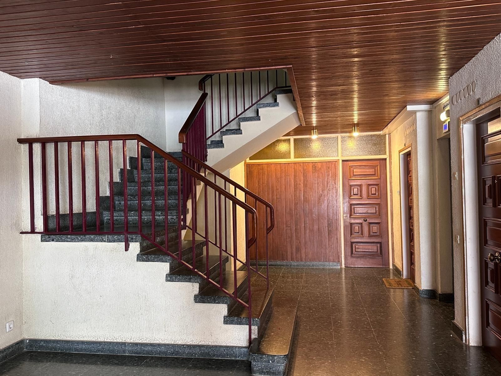 Un pasillo con escaleras y una puerta de madera.