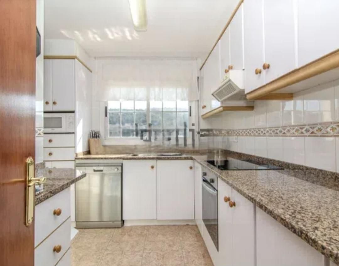 Cocina blanca con encimeras de granito y electrodomésticos de acero inoxidable.