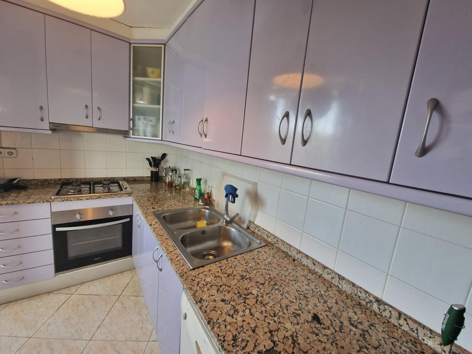 Una cocina con gabinetes morados y encimeras de granito.