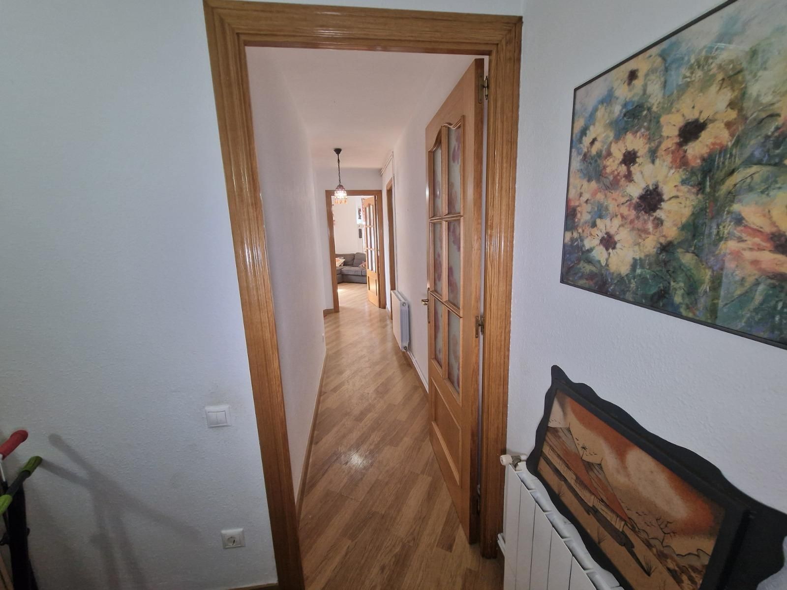 Un pasillo con un cuadro de flores en la pared.