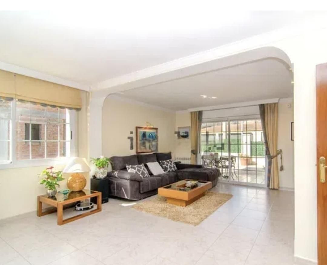 Sala de estar con sofá seccional gris, alfombra beige, mesa de café y puertas corredizas de vidrio que dan al patio.