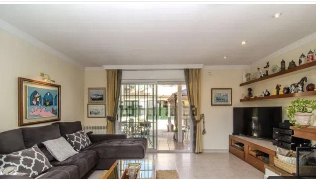 Sala de estar con sofá seccional gris oscuro, TV y puertas corredizas a un patio al aire libre.