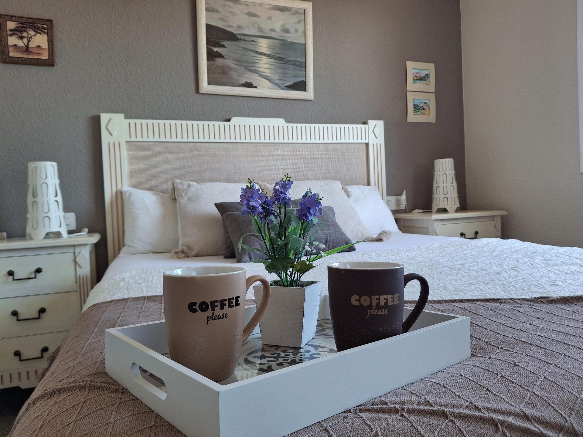 Dos tazas de café están en una bandeja sobre una cama.
