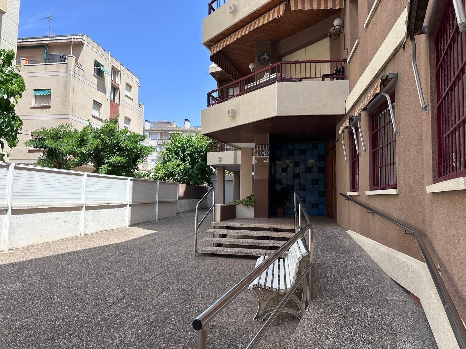 Un edificio con escaleras y un banco delante.