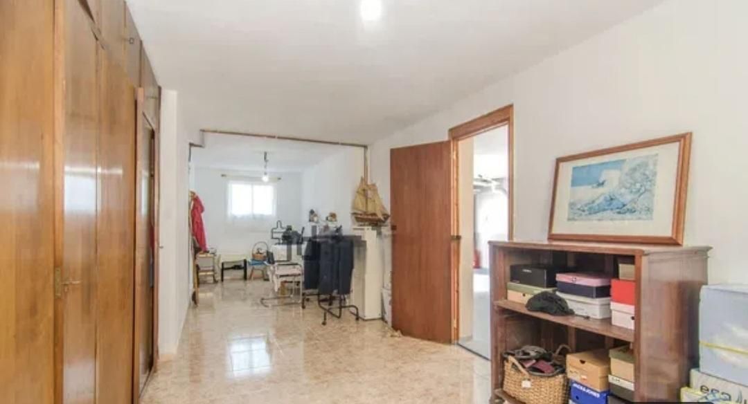 Pasillo con armario de madera, estantería y puerta abierta que da acceso a la sala de estar.