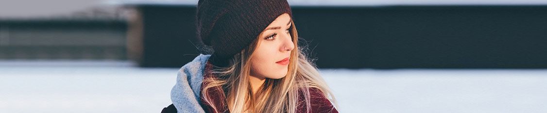 Una mujer que lleva una sudadera con capucha y una bufanda está parada en la nieve.