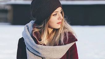 Una mujer que lleva un sombrero y una bufanda está parada en la nieve.