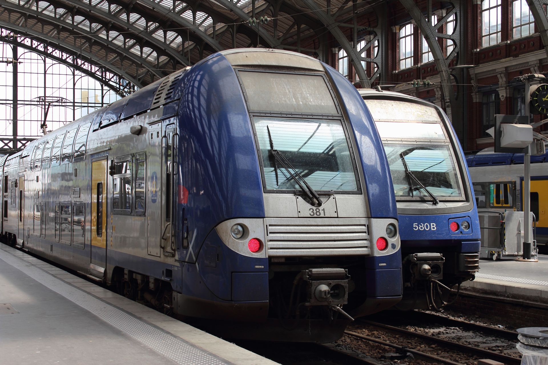 Deux trains bleus et argentés sur le quai d'une gare.
