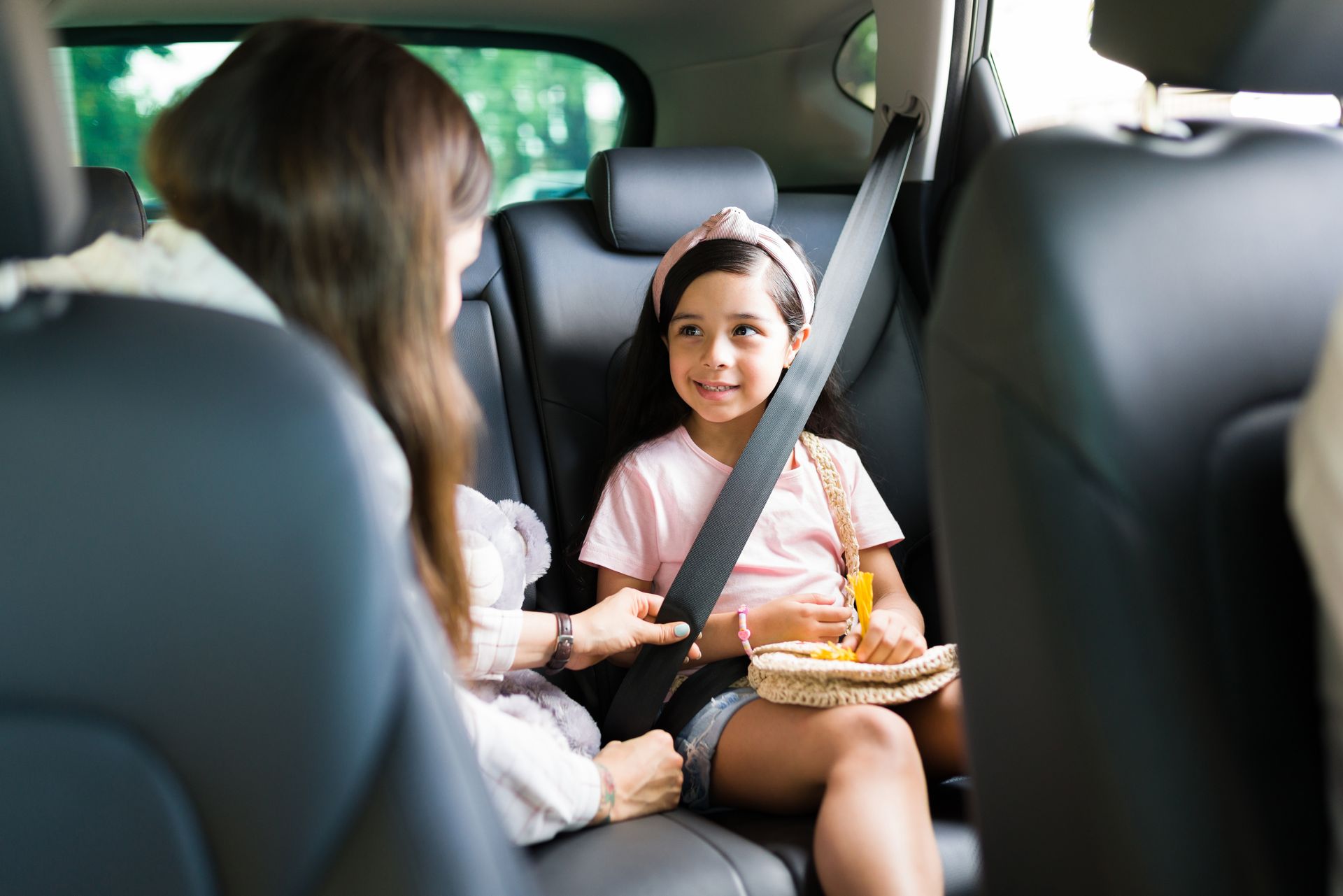 Deux personnes à bord d'une voiture, un enfant souriant avec sa ceinture de sécurité et un plateau-repas sur le siège arrière
