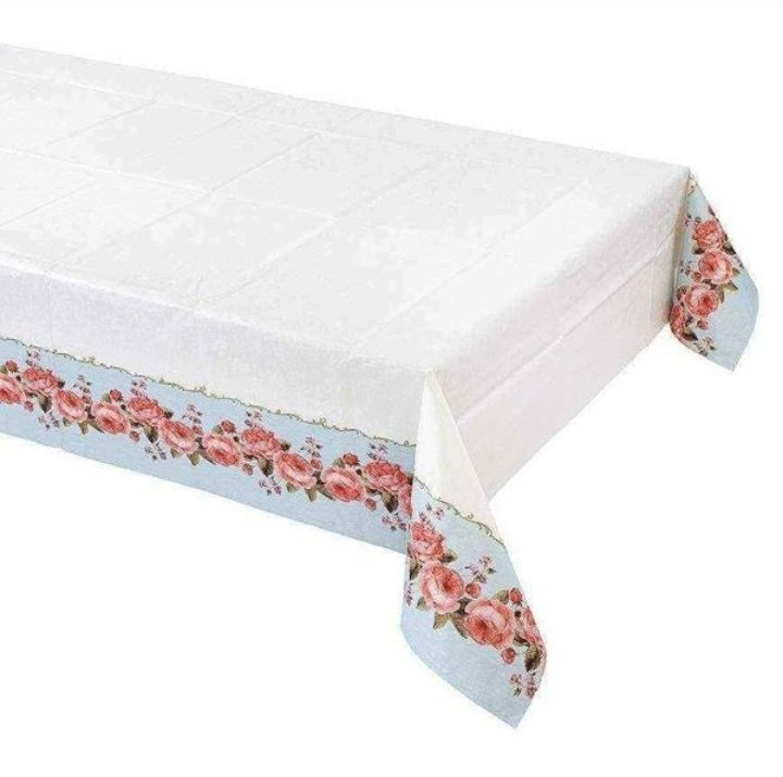 Elegante mesa puesta con centro de mesa floral y platos bajo delicadas cortinas blancas.