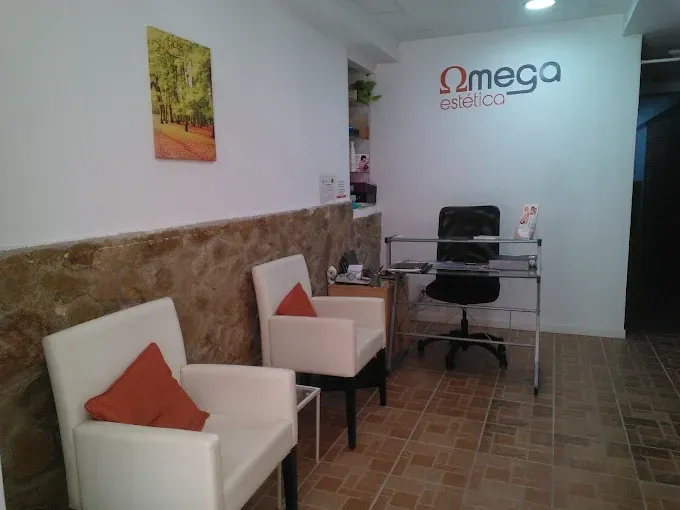 Una sala de espera con sillas blancas, almohadas naranjas y un escritorio bajo el logo de Omega Estética.