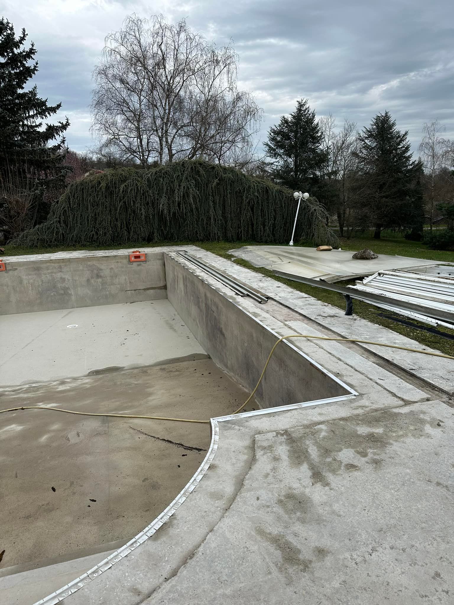 Piscine en béton vide en construction, ciel nuageux.