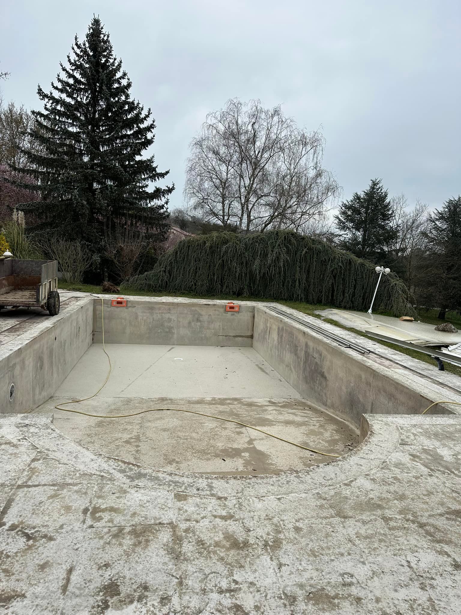 Piscine en béton vide en construction, journée nuageuse.