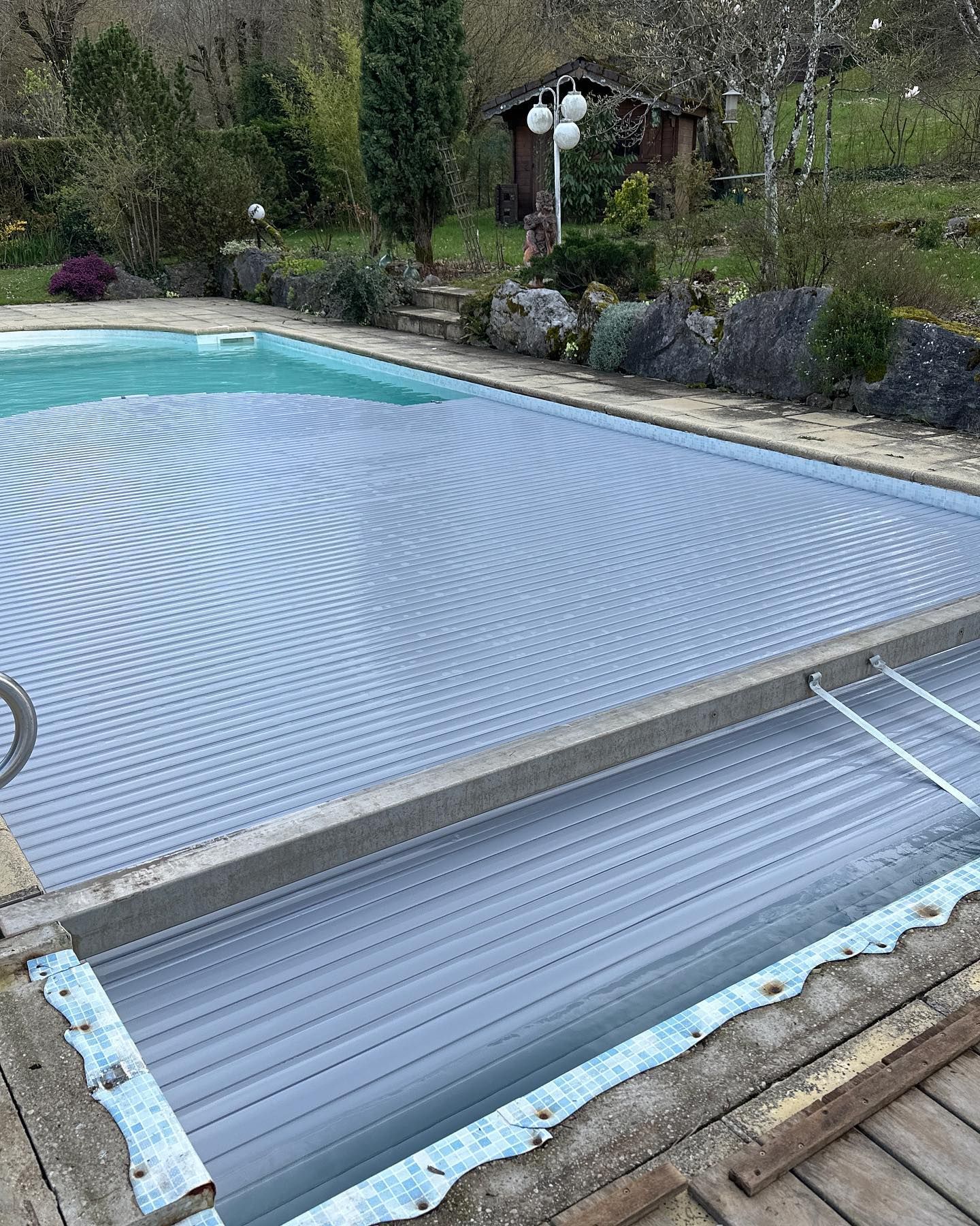 Piscine recouverte d'une protection, dans un aménagement d'arrière-cour, partiellement rétractée.