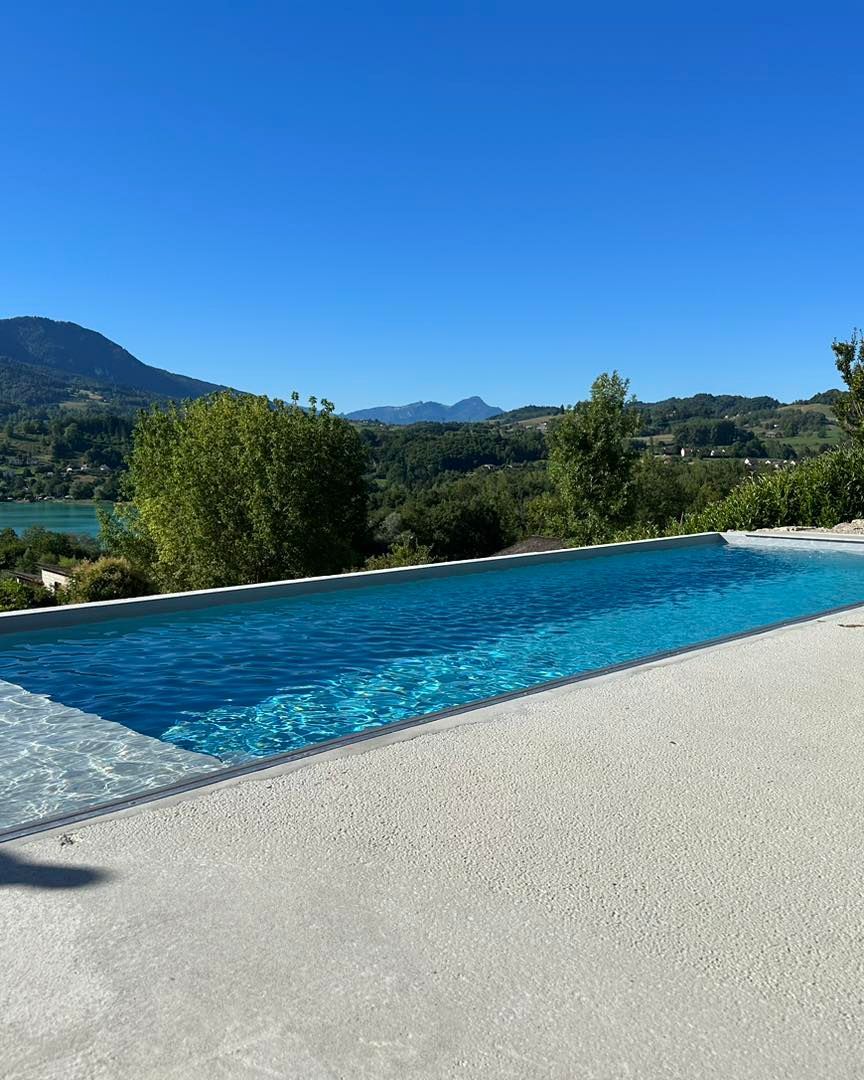 Piscine à l'eau bleu clair, surplombant un paysage pittoresque sous un ciel bleu éclatant.