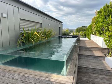 Piscine vitrée sur une terrasse en bois en haut d'un appartement.