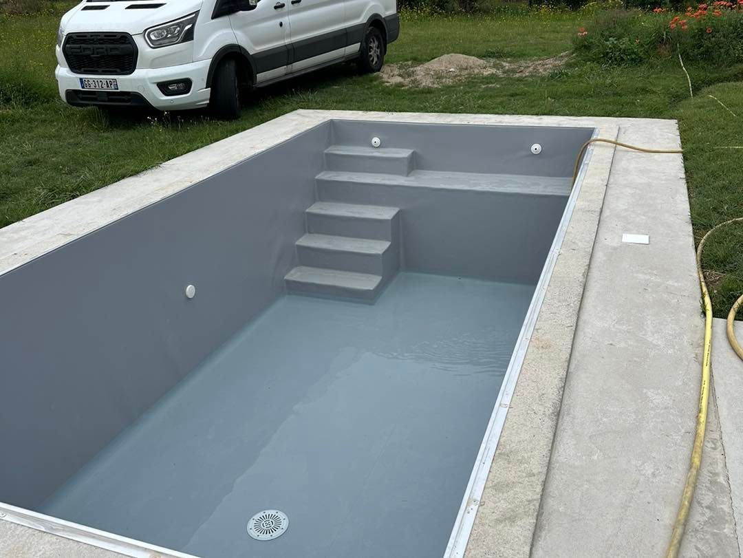 Piscine grise nouvellement construite avec marches et partiellement remplie d'eau.