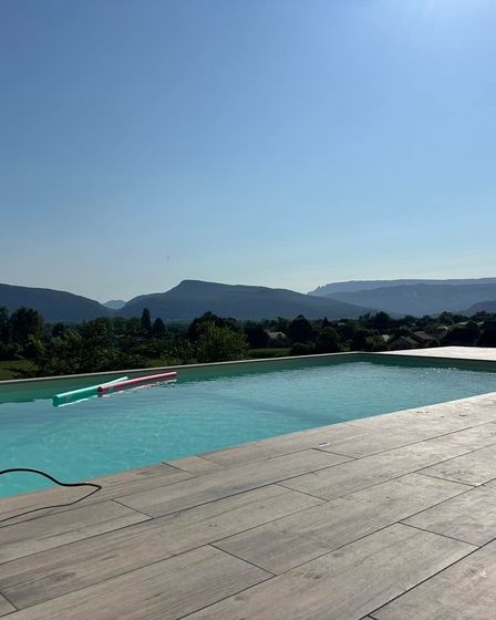 Piscine à débordement avec vue sur la chaîne de montagnes par une journée ensoleillée.