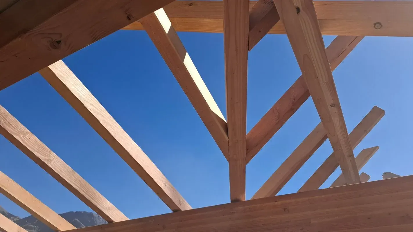 Poutres de toit en bois contre un ciel bleu clair.